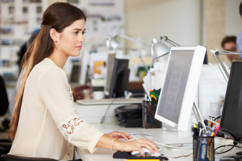 Woman Working At Desk In Busy Creative Office